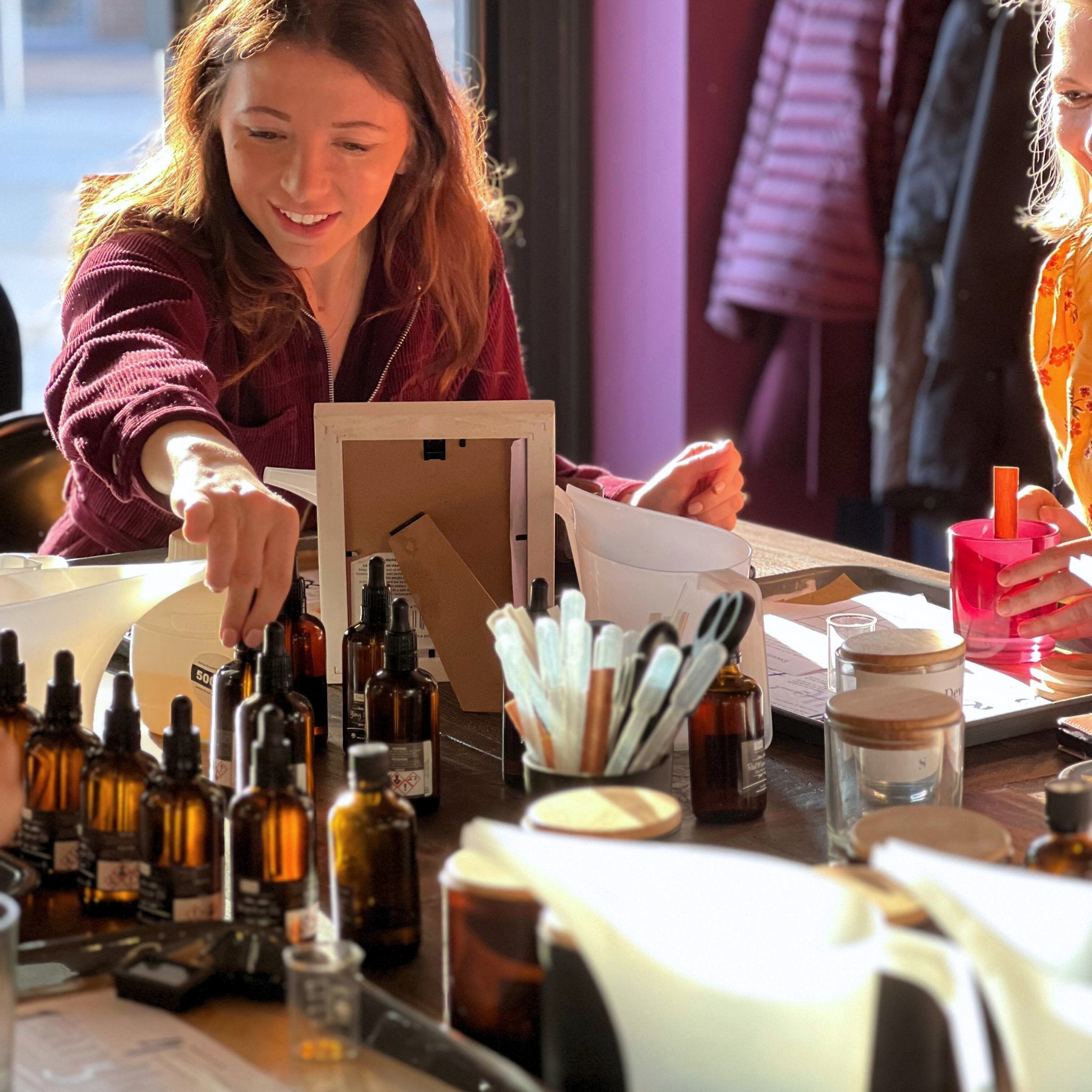 A lady picking up essential oil bottle during a Candle Making Workshop